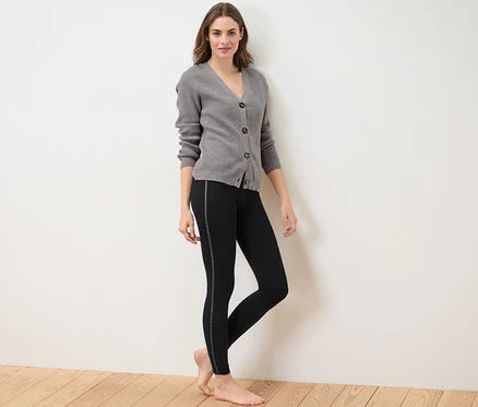 Femme posant en legging thermique avec bande scintillante et cardigan gris.