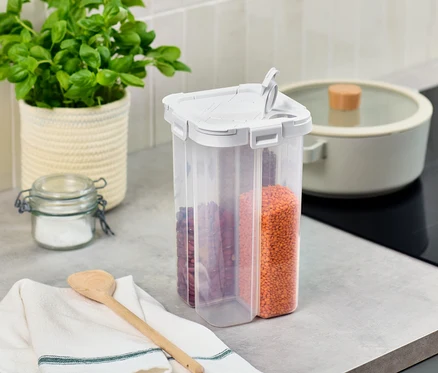 Sur un comptoir de cuisine, il y a une boîte de conservation 4 en 1, un pot de basilic et un pot en verre.
