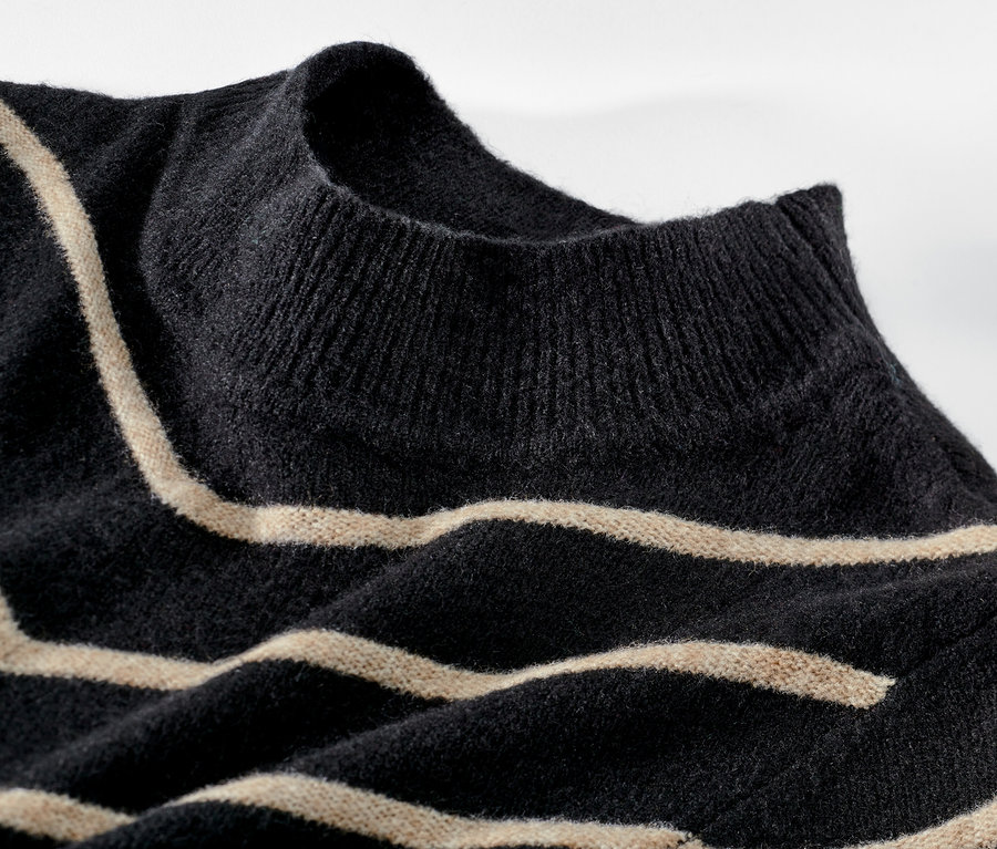 Gros plan d'un pull rayé en maille noire à col montant.