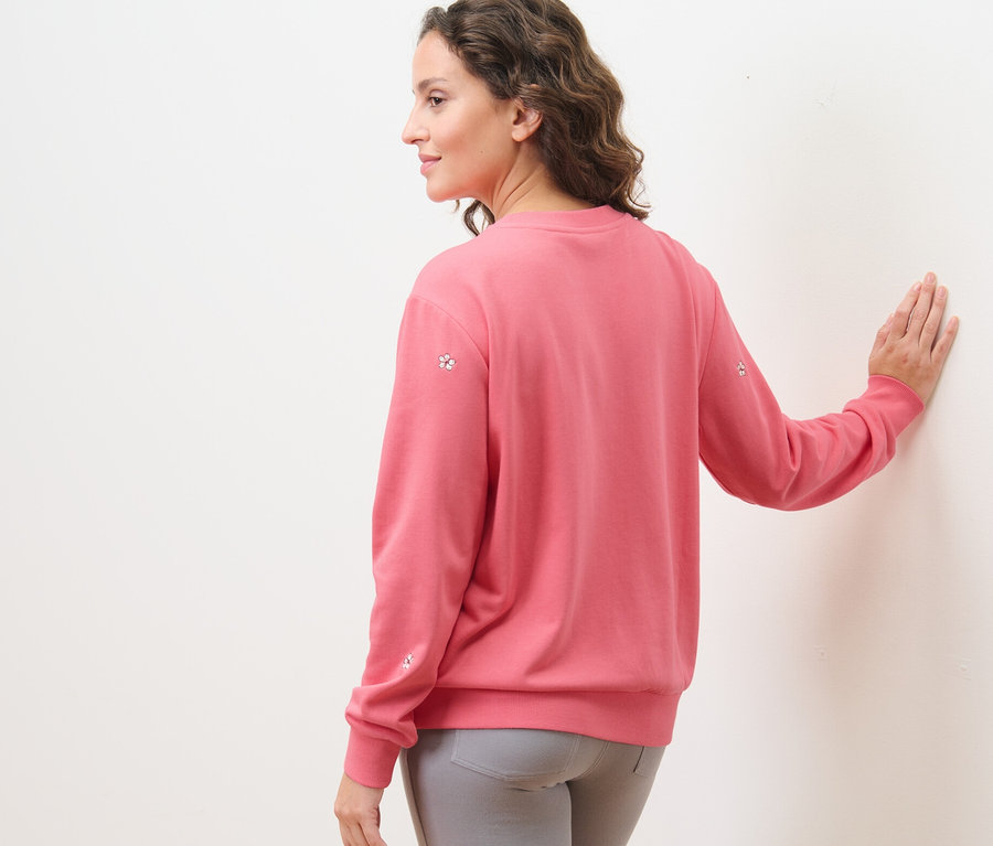 Une femme portant un sweat-shirt brodé et un pantalon gris.