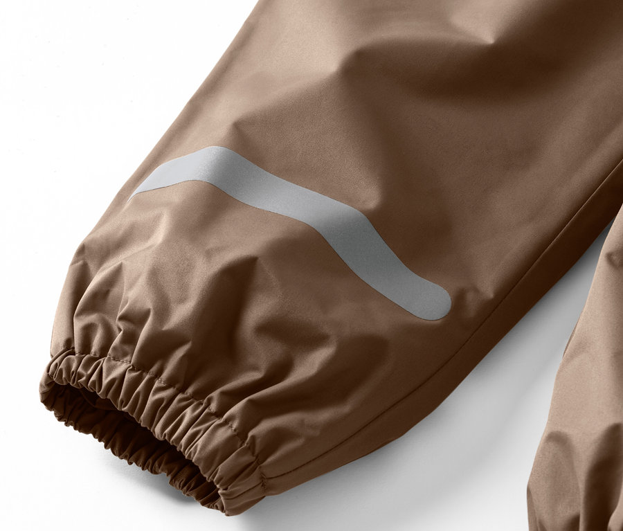 Gros plan sur un pantalon de pluie pour enfant avec une bande réfléchissante sur la jambe.