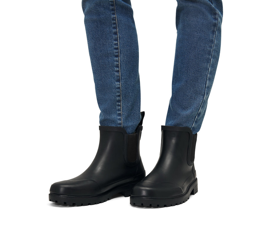 Jambes en jean et bottines de pluie.