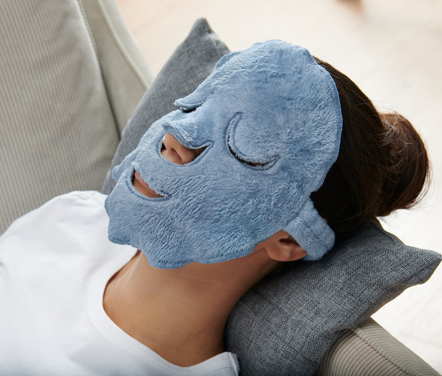 Femme allongée sur un oreiller avec 2 masques pour le visage bleus.