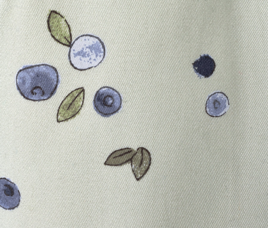 Gros plan du motif d'un pantalon à enfiler pour enfant – Coupe « Ella », myrtilles sur un tissu vert clair.
