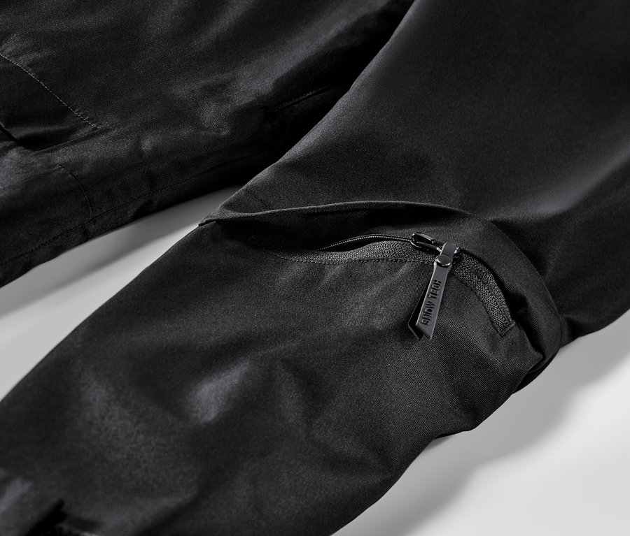 Détail d'une veste de ski noire avec fermeture éclair et poche.