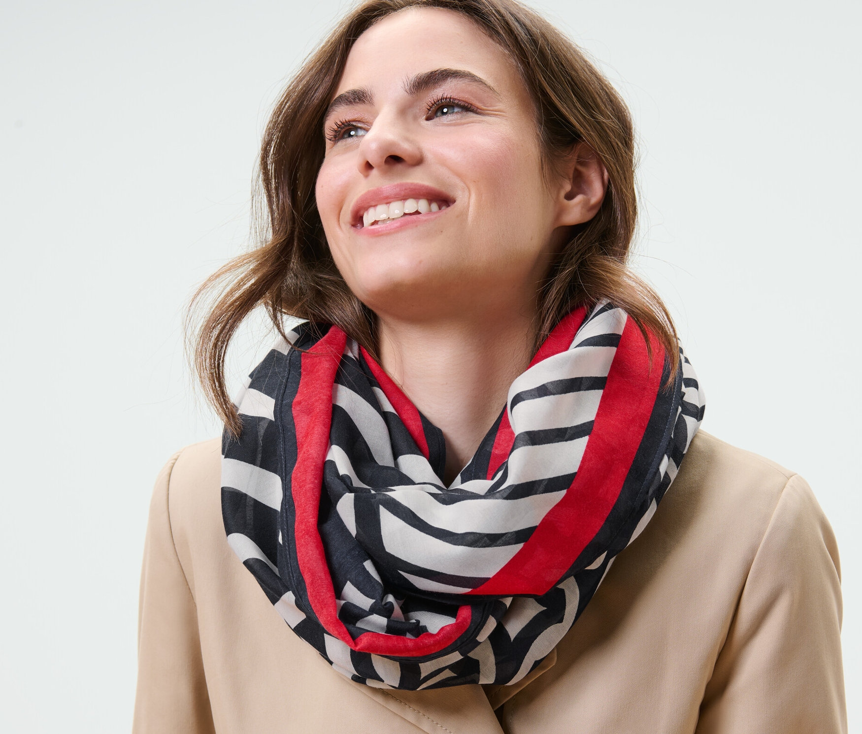 Femme souriant et portant un foulard loop imprimé.