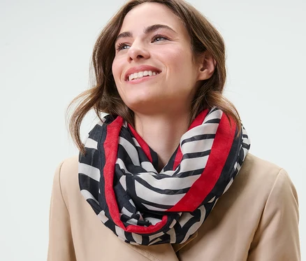 Femme souriant et portant un foulard loop imprimé.