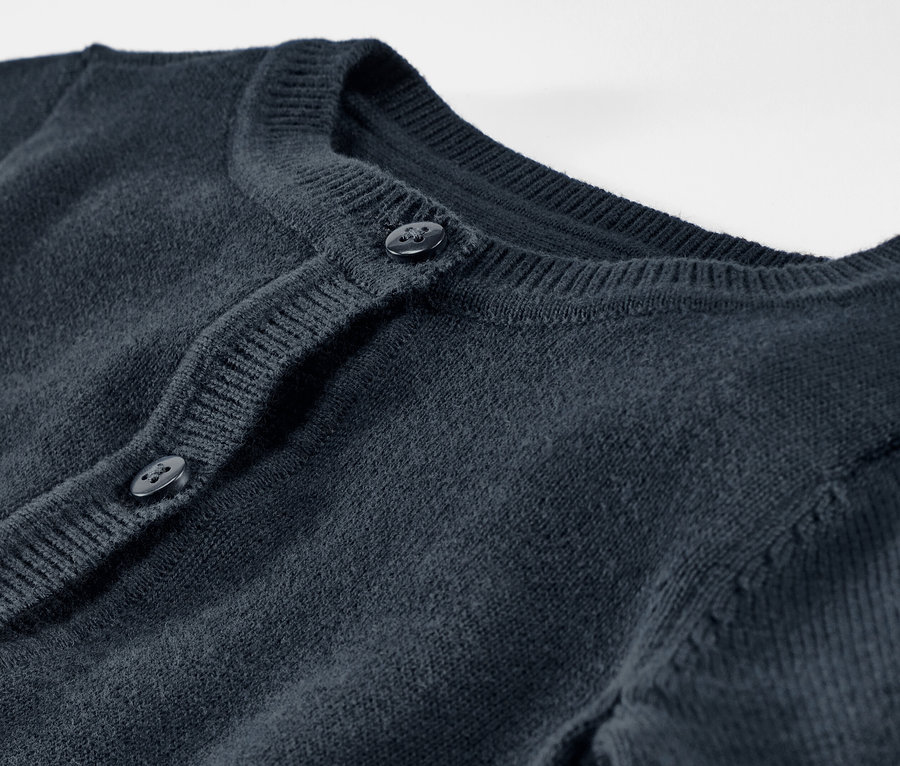 Gros plan sur une jaquette en maille pour enfant avec des boutons.