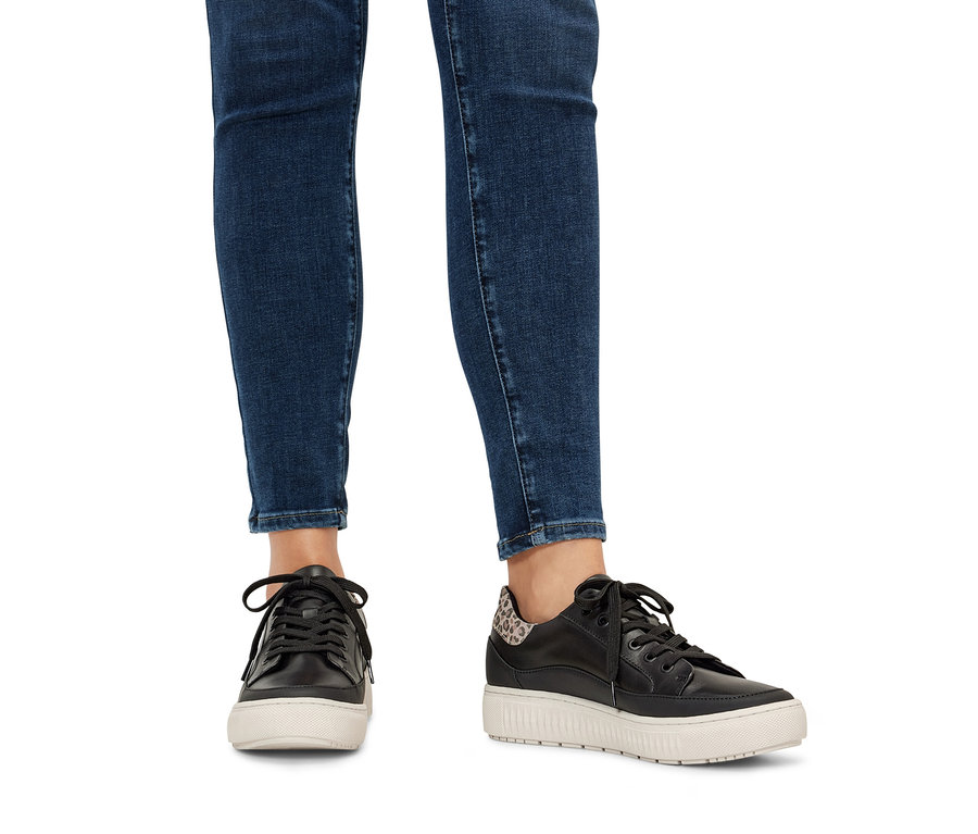 Jambes en jean et baskets en cuir.