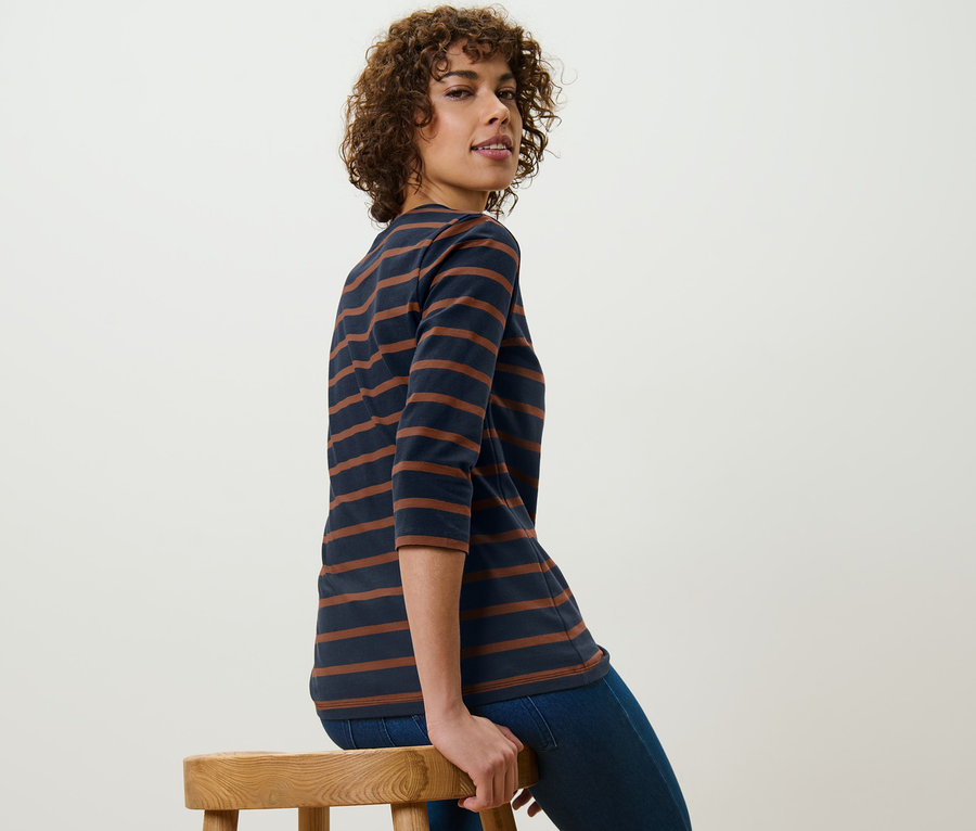 Femme assise sur un tabouret portant un t-shirt manches 3/4 à rayures.