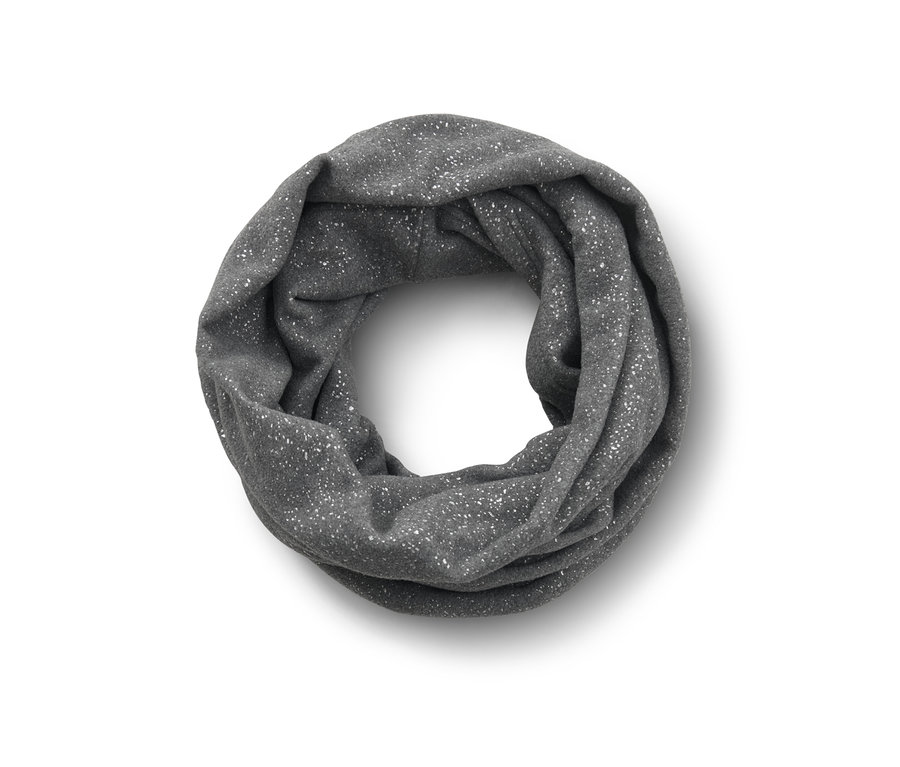 Une écharpe-tube scintillante grise est posée, pliée sur une surface blanche.