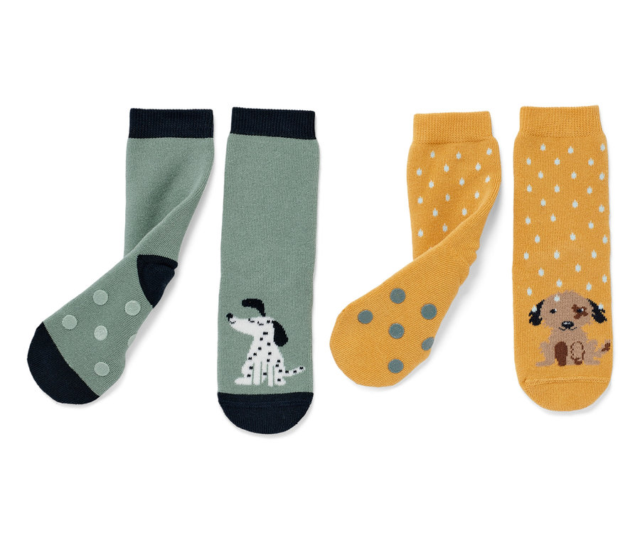 Deux paires de chaussettes anti-dérapantes pour enfant : une paire verte avec un motif de dalmatien, une paire jaune avec un motif de chiot.