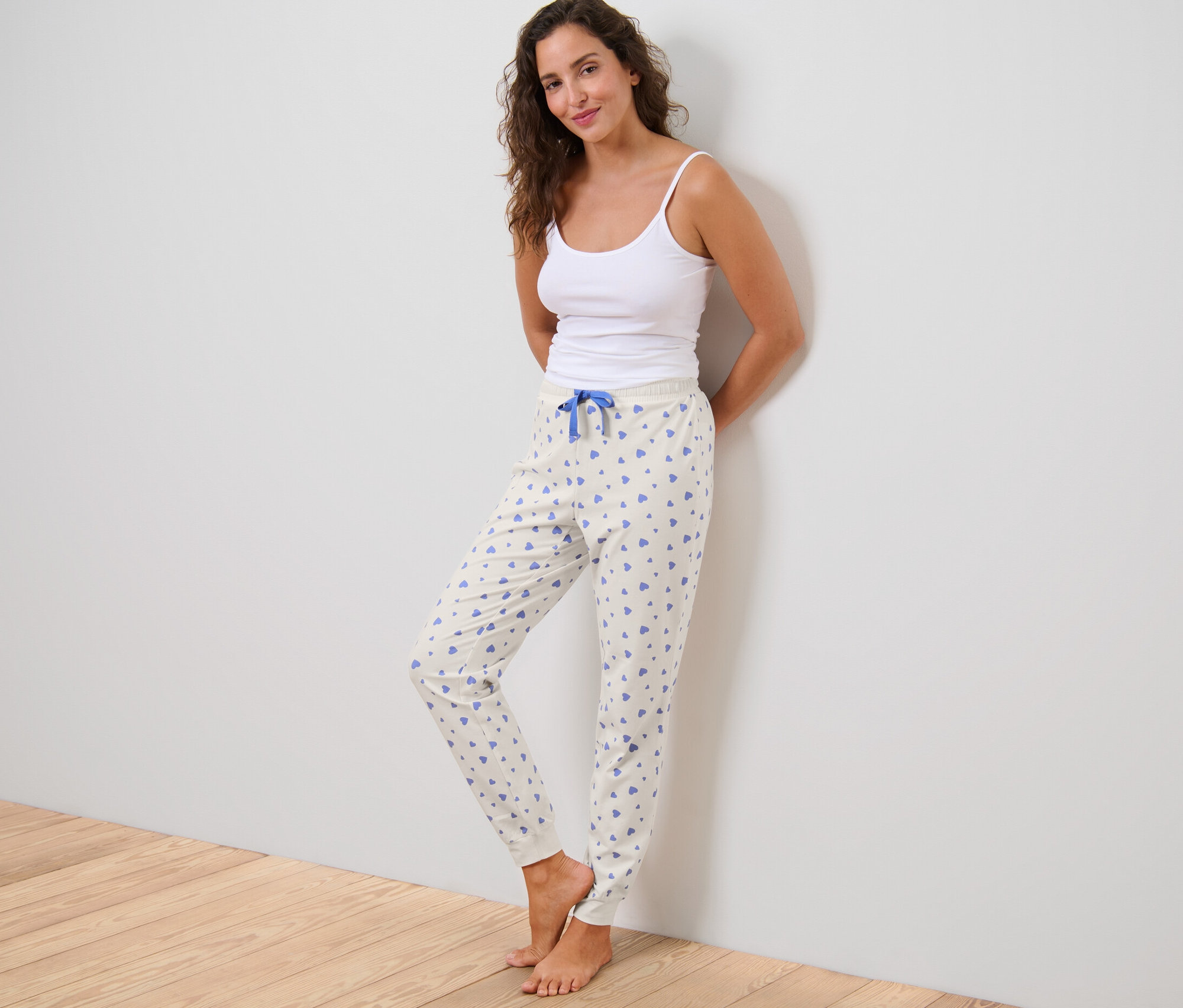 Femme en débardeur posant en pantalon de pyjama à cœurs.