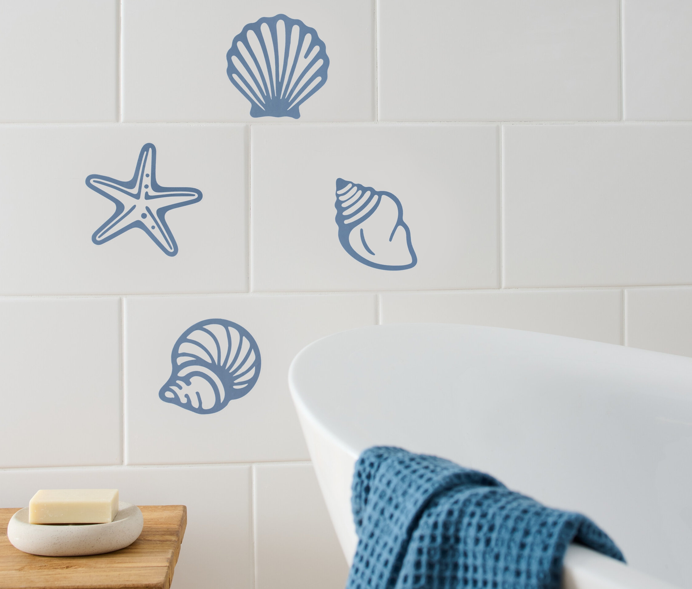 Autocollants pour carrelage à motifs maritimes sur des carreaux blancs dans une salle de bain.