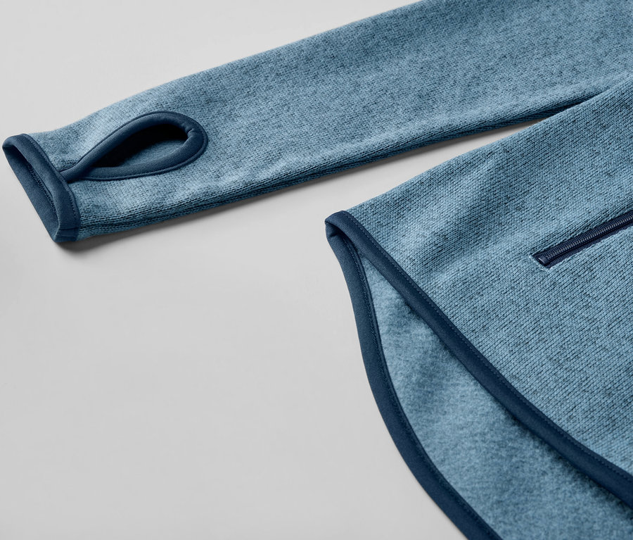 Détail d'une veste en polaire tricotée bleu foncé avec un trou pour le pouce.