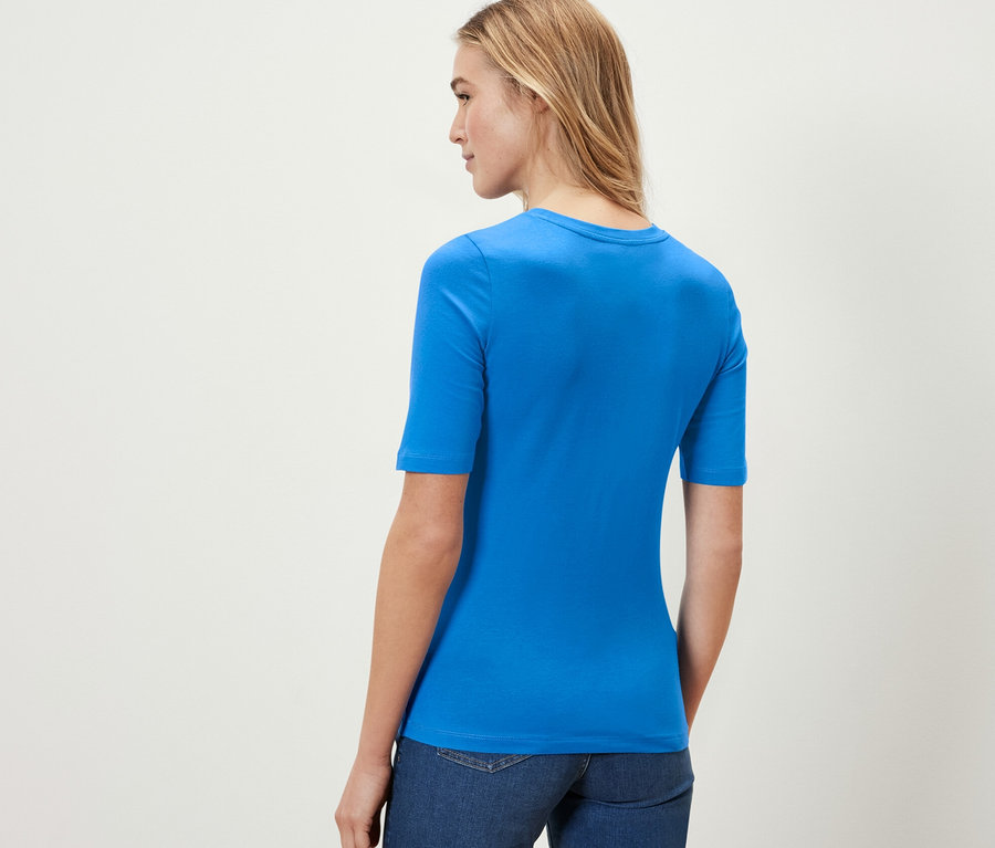 Une femme porte un t-shirt à manches courtes bleu cobalt et un jean.