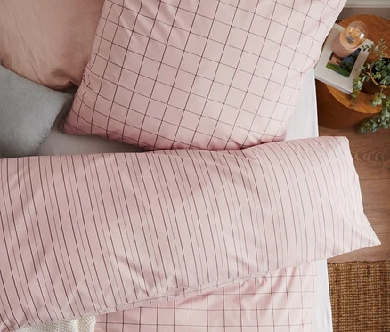 Vue de dessus d'un lit avec une parure de lit en coton de qualité supérieure de taille standard et grande taille avec un motif à carreaux et un oreiller rayé.