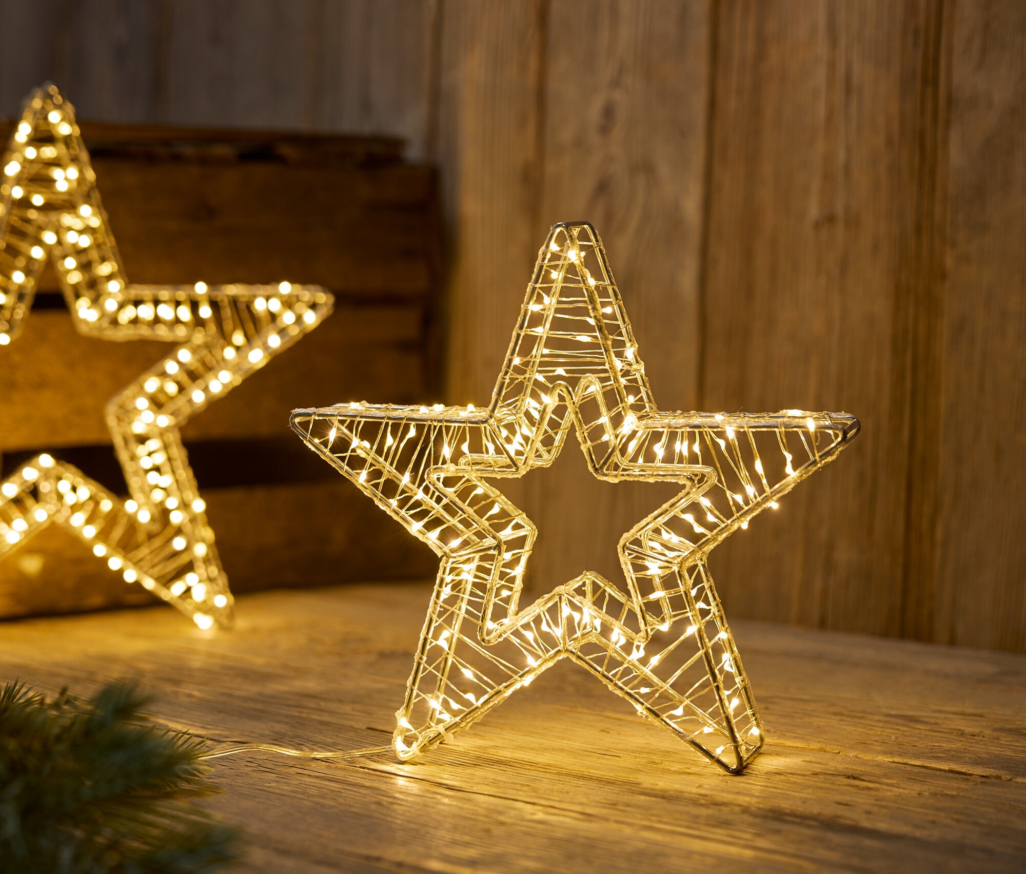 Étoiles en fil de fer illuminées sur une surface en bois.