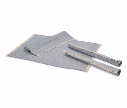 Deux tapis gris enroulés et un tapis gris déroulé avec des franges.