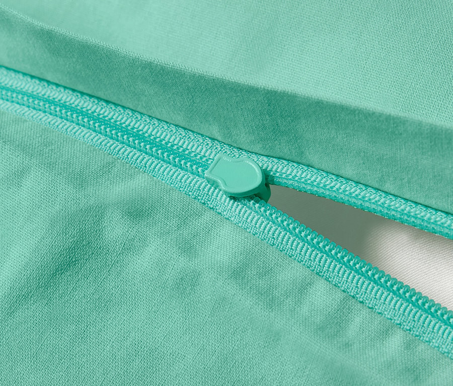 Gros plan d'une parure de lit en renforcé turquoise avec fermeture éclair.