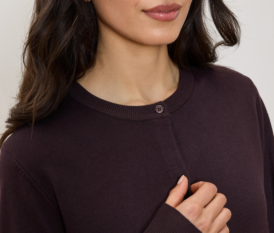Haut du corps d'une femme portant un cardigan bordeaux à col rond avec un bouton.