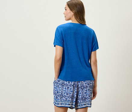 Femme posant de dos portant un t-shirt en lin mélangé bleu cobalt et un short bleu et blanc.