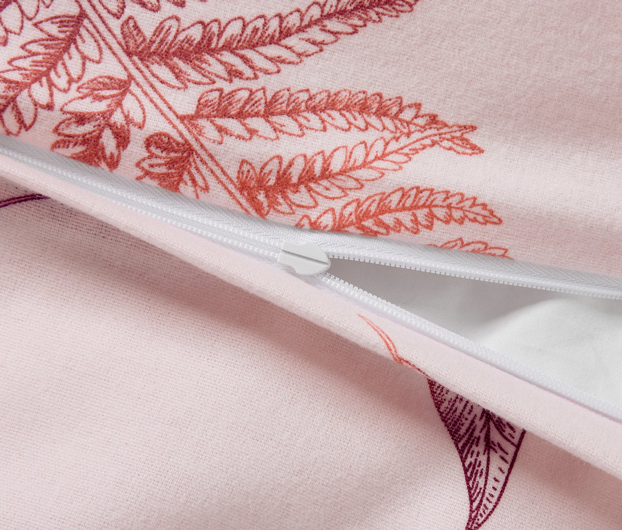 Gros plan d'une housse de couette rose avec un motif de fougères et une fermeture éclair blanche.