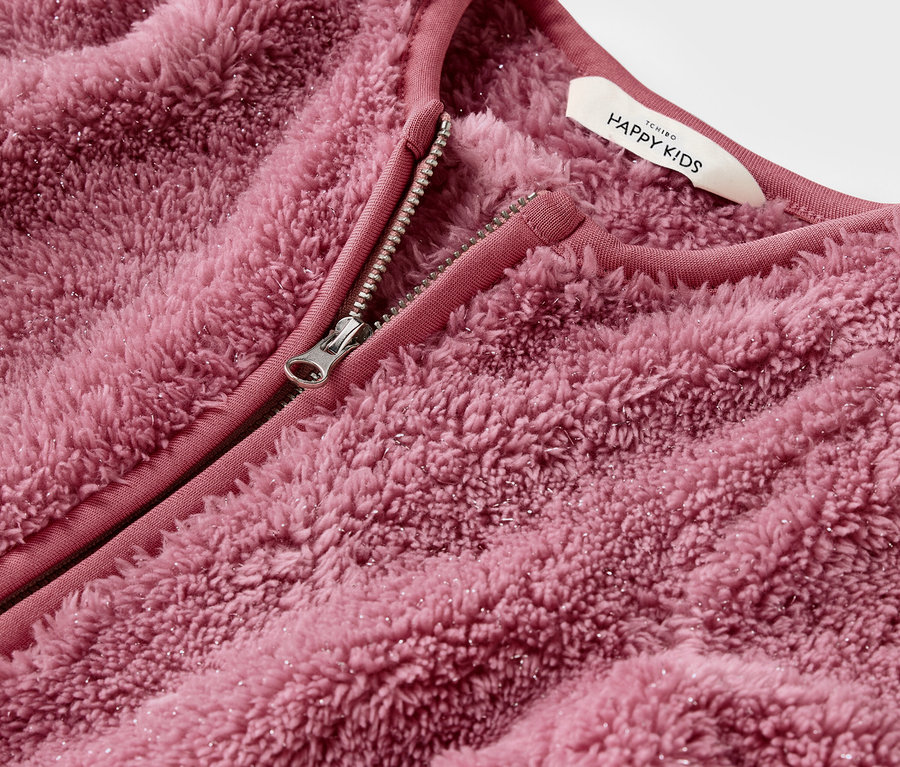 Gros plan sur une veste rose duveteuse avec une fermeture éclair ouverte.