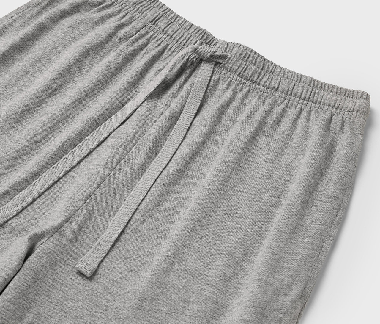 Gros plan sur un pantalon de survêtement gris avec une taille élastique et un cordon de serrage.