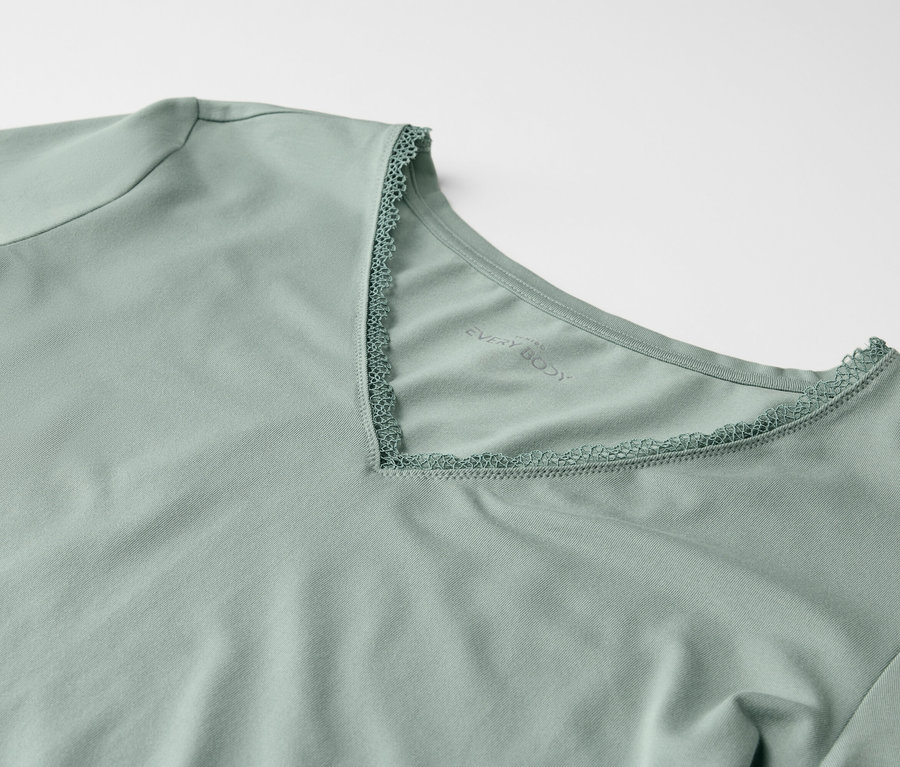 Vue détaillée d'un t-shirt vert clair à manches courtes et à encolure en V ornée de dentelle.
