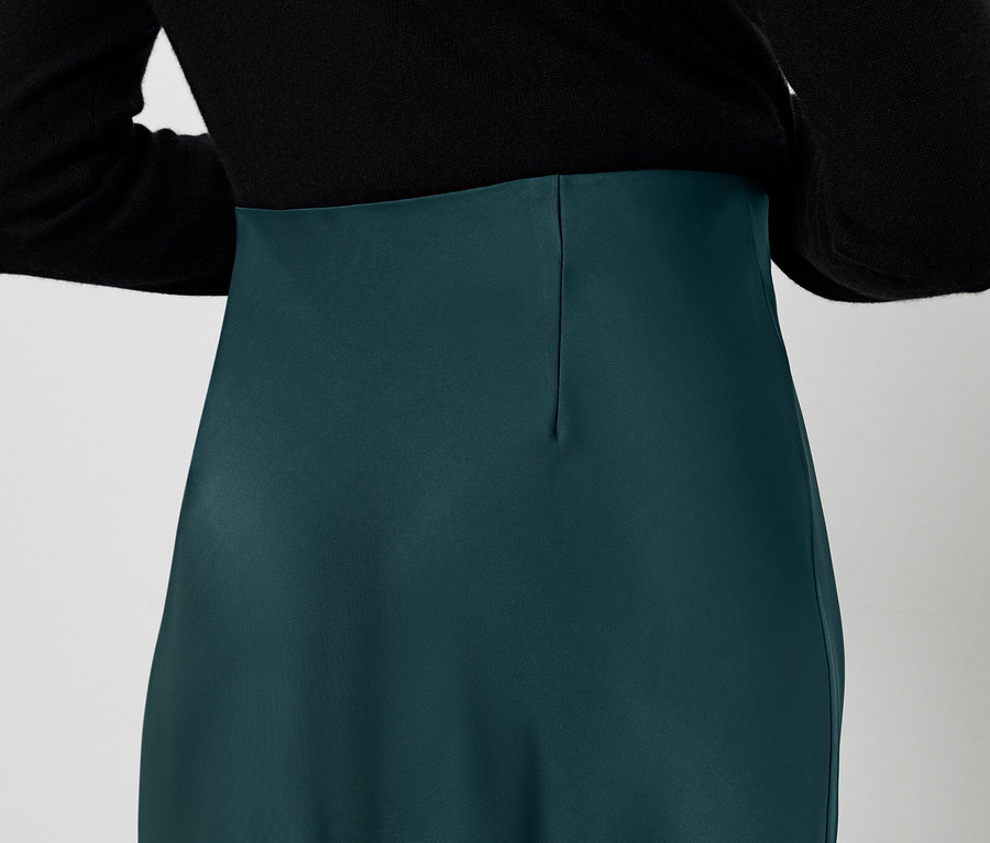 Vue arrière d'une femme portant un chemisier noir et une jupe verte.
