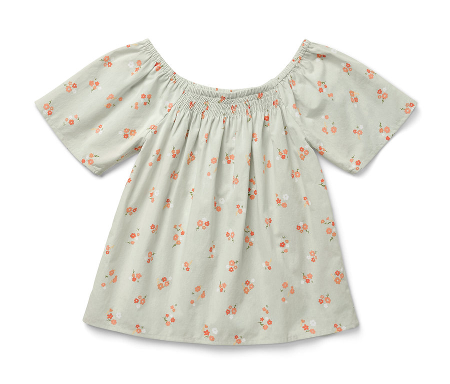 Une blouse pour enfant avec un motif floral sur un fond clair.