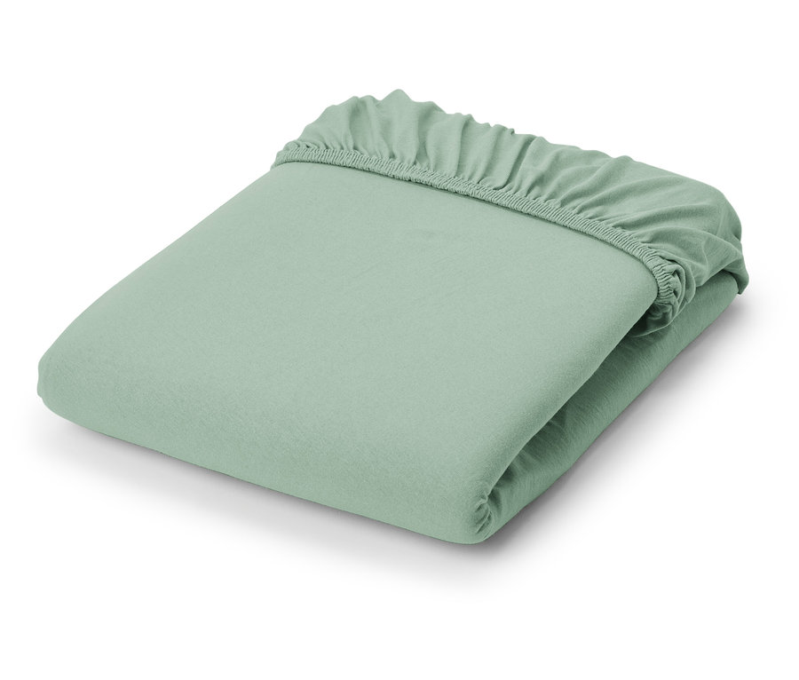 Un drap-housse en jersey vert clair plié.