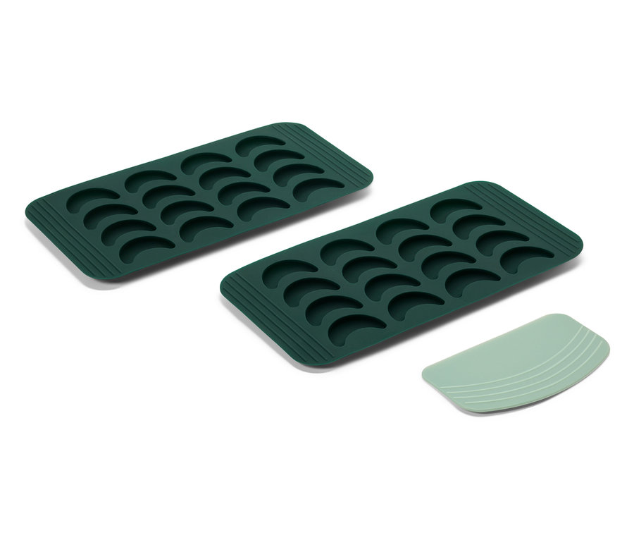 Deux moules à glaçons en silicone verts et une spatule verte sur fond blanc.