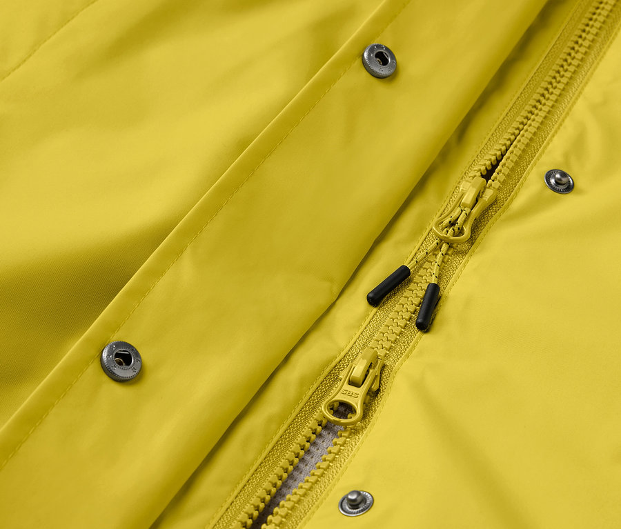 Gros plan sur une veste jaune avec des boutons-pression argentés et une fermeture éclair jaune.