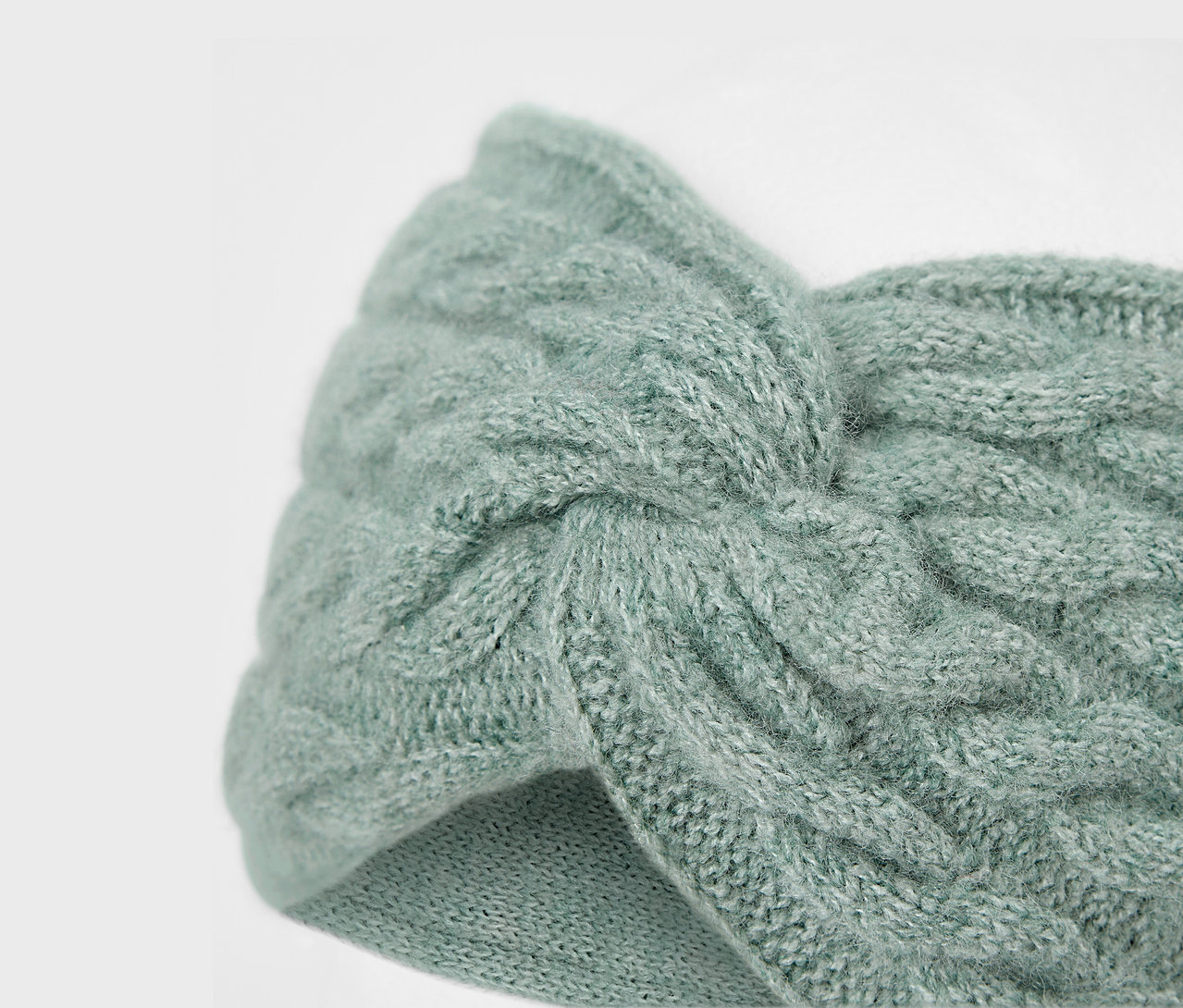 Gros plan d'un bandeau tricoté bleu clair avec un motif de torsades.