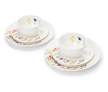 Deux tasses blanches à motifs floraux sur des assiettes.