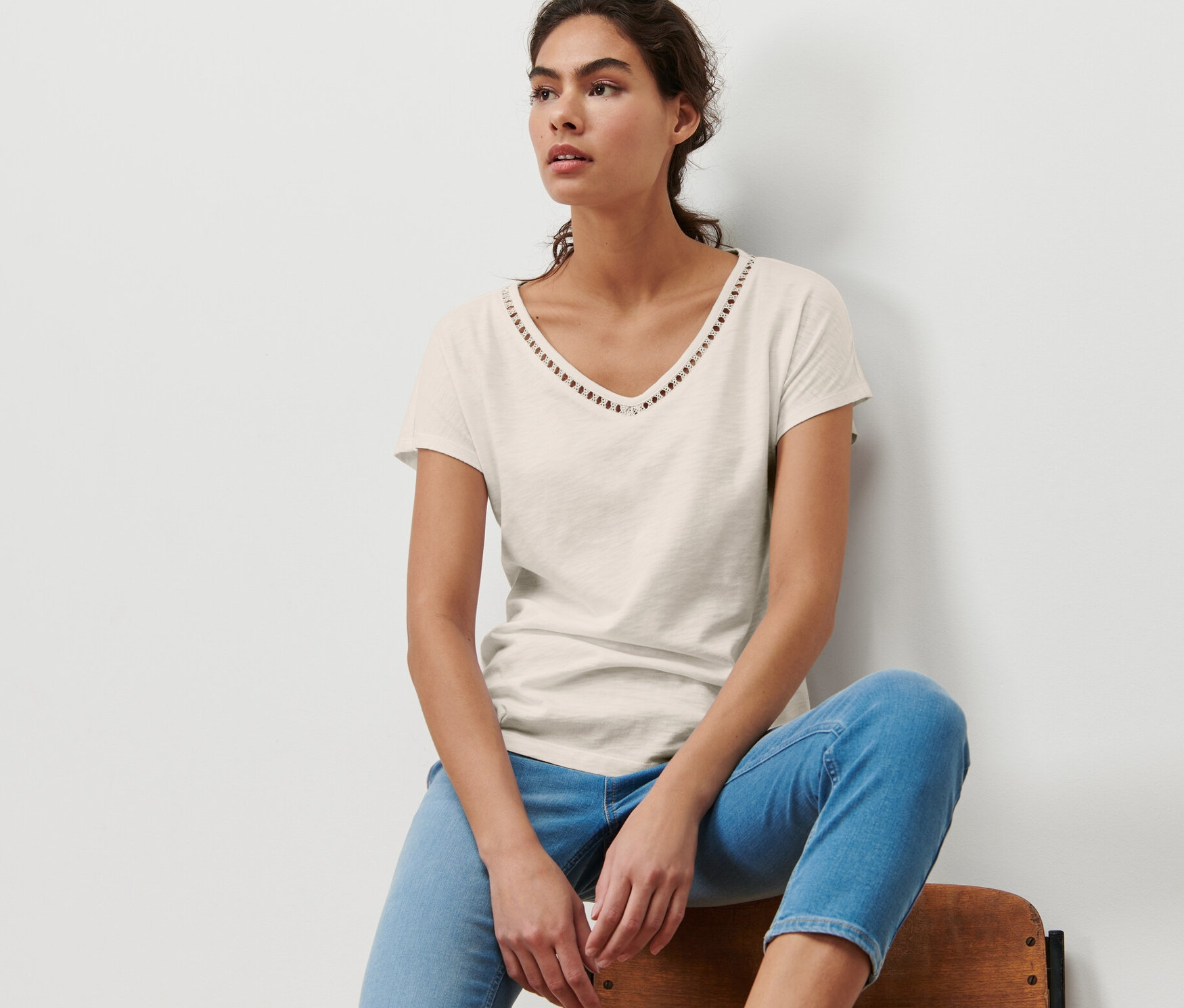 Une femme est assise sur une chaise et porte un t-shirt en mélange avec modal, blanc crème.