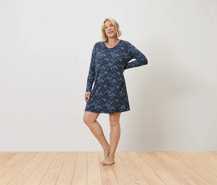 Femme posant dans une chemise de nuit bleue à motifs avec des manches longues.