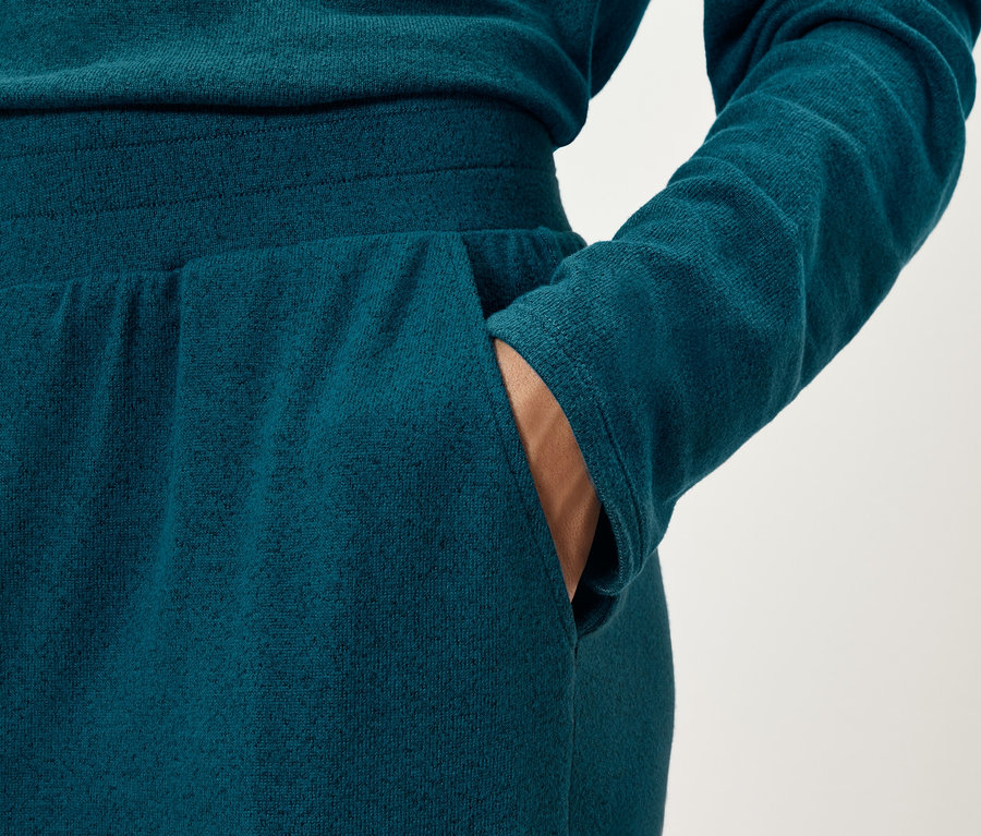 Gros plan d'une femme portant un pantalon de survêtement bleu marine et mettant sa main dans sa poche.