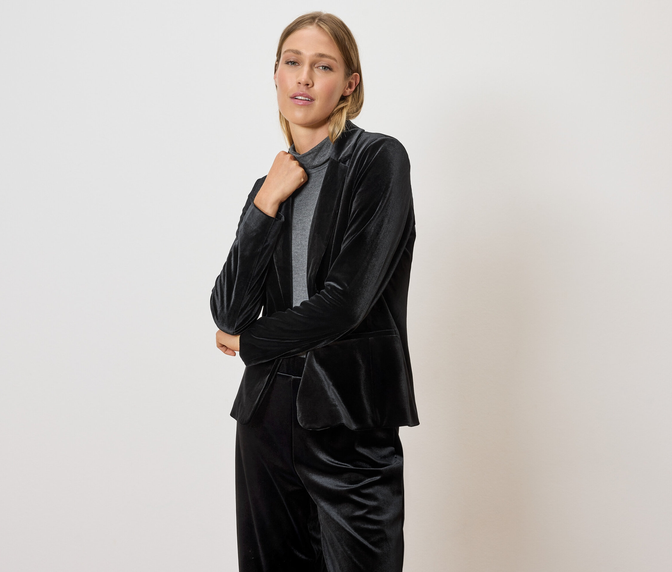 Femme posant dans un blazer et un pantalon en velours noir.