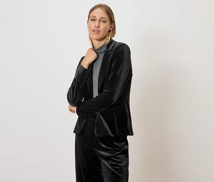 Femme posant dans un blazer et un pantalon en velours noir.