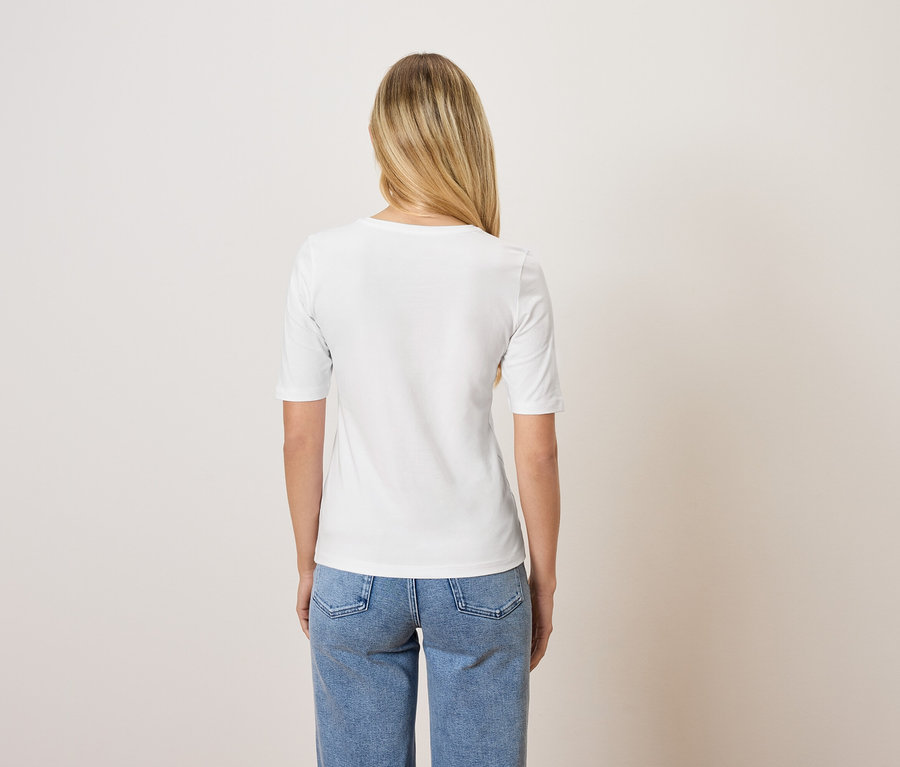 Vue arrière d'une femme blonde portant un t-shirt blanc et un jean bleu.