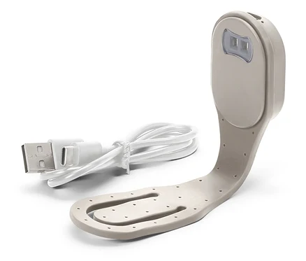 Gros plan d'une lampe de lecture beige avec un câble USB blanc.