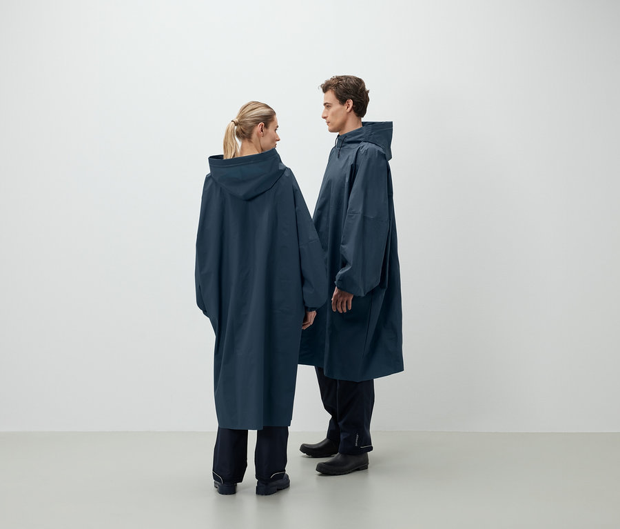 Un homme et une femme se font face et portent des ponchos de pluie bleu foncé à capuche.