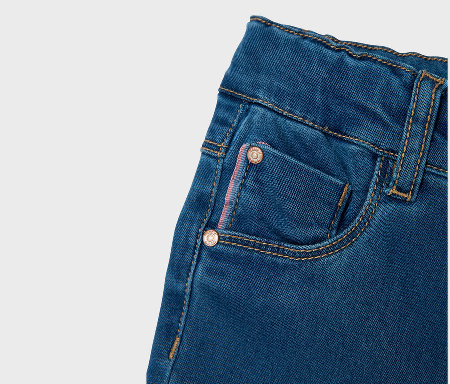 Gros plan d'un jean bleu avec une petite poche et des coutures.