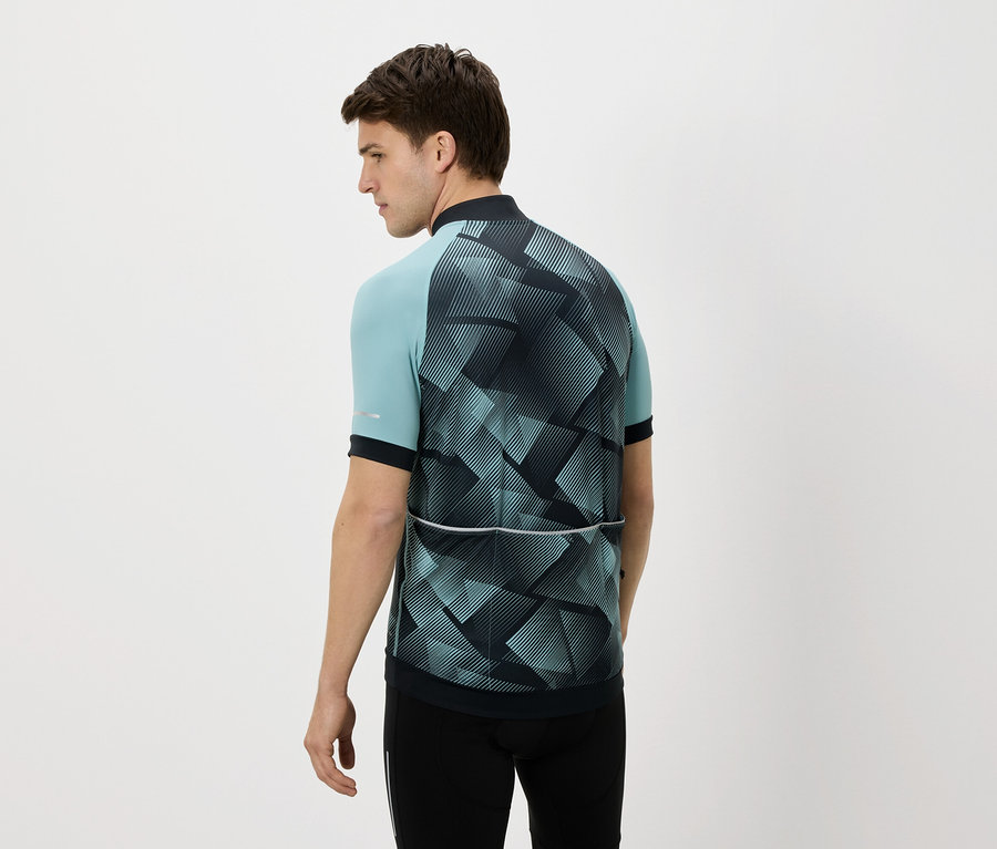 Homme vu de dos portant un maillot de cyclisme bleu et noir et un pantalon noir sur un fond blanc.