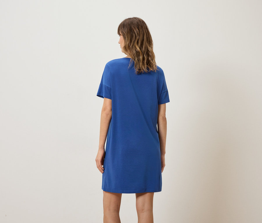Femme vue de dos portant une robe bleue en forme de T-shirt.