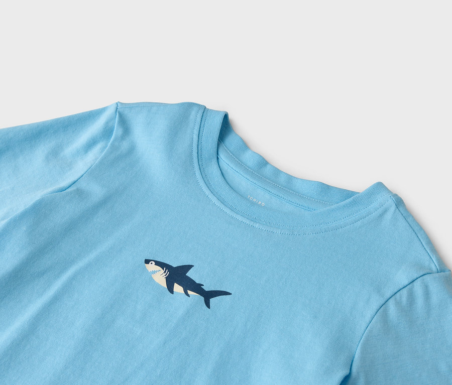 Gros plan sur un t-shirt bleu clair avec un motif de requin.