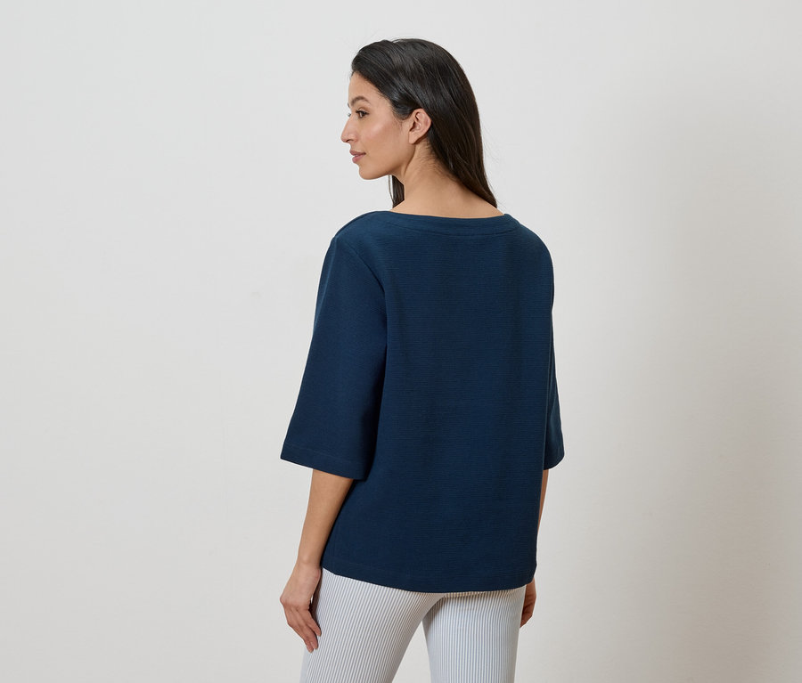 Femme portant un haut bleu marine et un pantalon rayé, vue de dos.